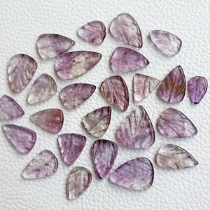 May include: A collection of 25 purple and clear faceted gemstone pendants with a leaf design. The pendants are carved from amethyst and are ideal for jewellery making.