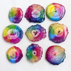May include: Nine rainbow agate slices with a white center and a variety of colors, including red, orange, yellow, green, blue, and purple.