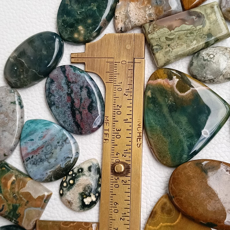 May include: A collection of polished green, brown, and gray stones with a ruler measuring up to 2 1/2 inches.
