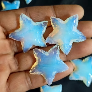 May include: A collection of five iridescent blue opal star-shaped stones. The stones are smooth and polished, with a variety of sizes and shapes.
