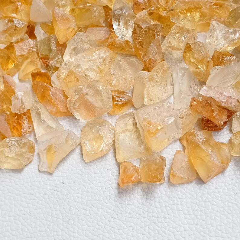May include: A pile of small, rough, translucent, yellow-orange citrine crystals.