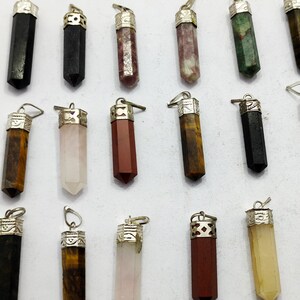 May include: Assortment of 15 crystal point pendants with silver caps. The crystals are in various colours, including black, green, pink, brown, and red.
