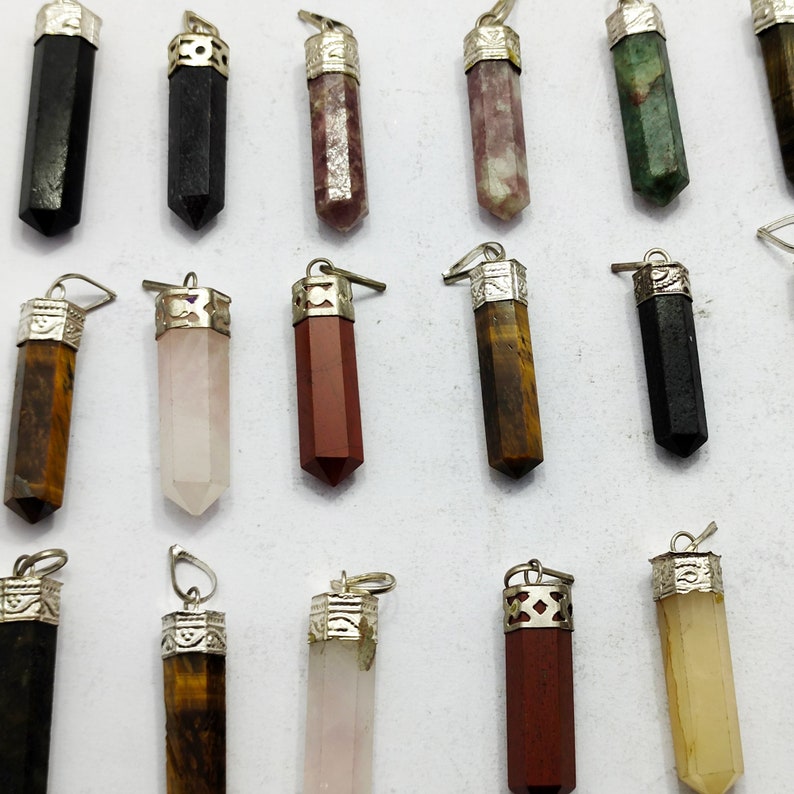 May include: Assortment of 15 crystal point pendants with silver caps. The crystals are in various colours, including black, green, pink, brown, and red.
