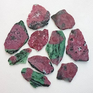 Może przedstawiać: Kolekcja dziesięciu surowych, naturalnych, r&oacute;żowych i zielonych odłamk&oacute;w kamieni szlachetnych. Odłamki mają nieregularne kształty i r&oacute;żne rozmiary.