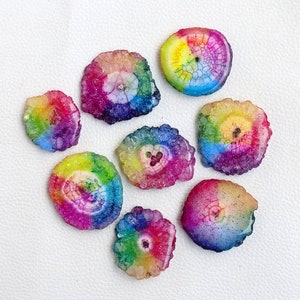 May include: Eight rainbow agate slices with a variety of colors and patterns. The slices are all about 2 inches in diameter and have a natural, rough edge.