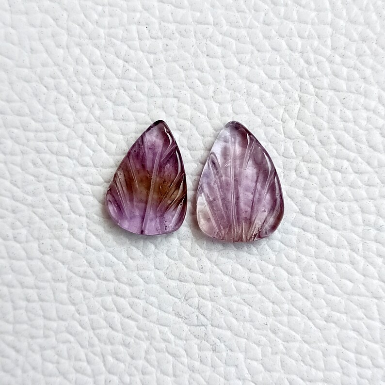 May include: Two carved amethyst gemstone pendants in a teardrop shape with a purple and brown colour gradient.