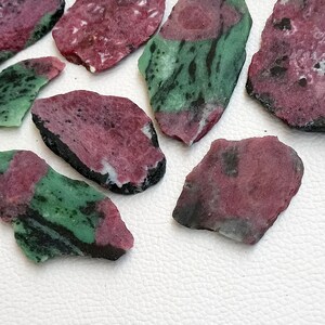 Może przedstawiać: Zbi&oacute;r zielonych i r&oacute;żowych odłamk&oacute;w kamieni szlachetnych. Odłamki mają nieregularny kształt i szorstką, naturalną fakturę.