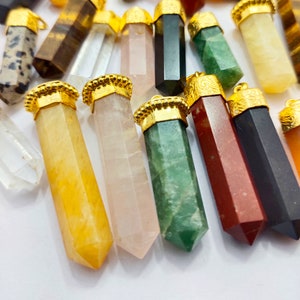 May include: A collection of colourful gemstone pendants with gold accents. The pendants are in various shapes and sizes, including clear, yellow, pink, green, red, and black.