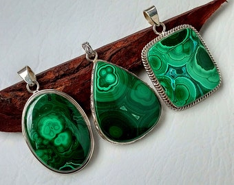 Pode incluir: Três pingentes de prata com pedras de malaquita verde. As pedras são de formas e tamanhos diferentes e têm um padrão de redemoinho.