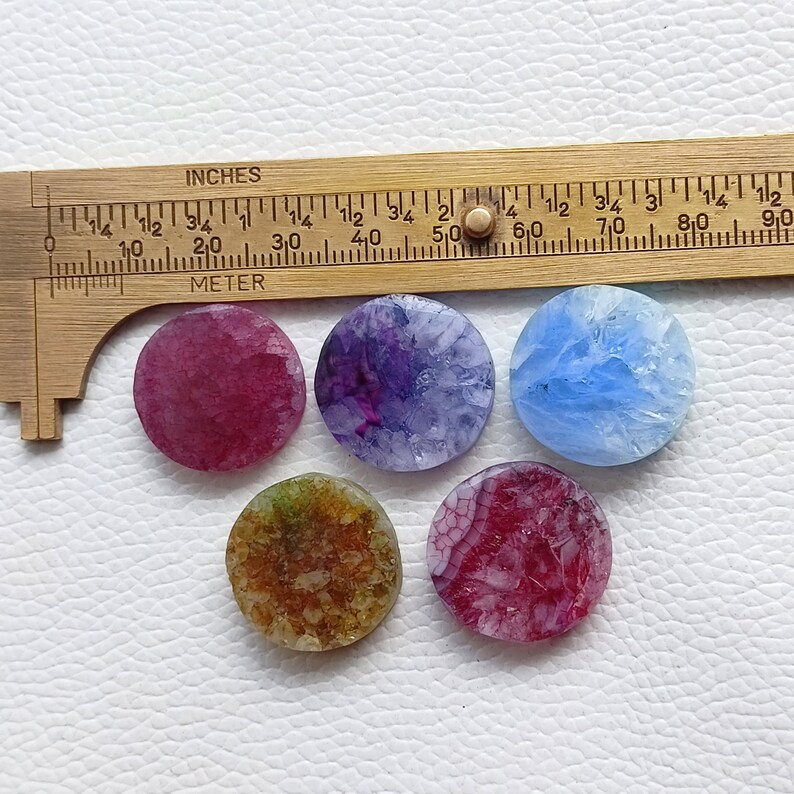 May include: Six round agate slices in various colors, including pink, purple, blue, and brown. The agate slices are approximately 1 inch in diameter.
