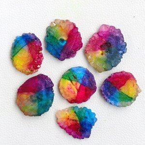 May include: Seven rainbow crystal clusters in various shapes and sizes. The crystals are a mix of pink, purple, blue, green, yellow, and orange.
