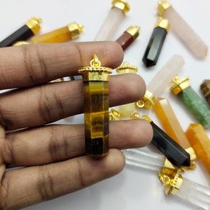 May include: A collection of gemstone pendants with gold caps, including tiger's eye, clear quartz, rose quartz, and green aventurine.