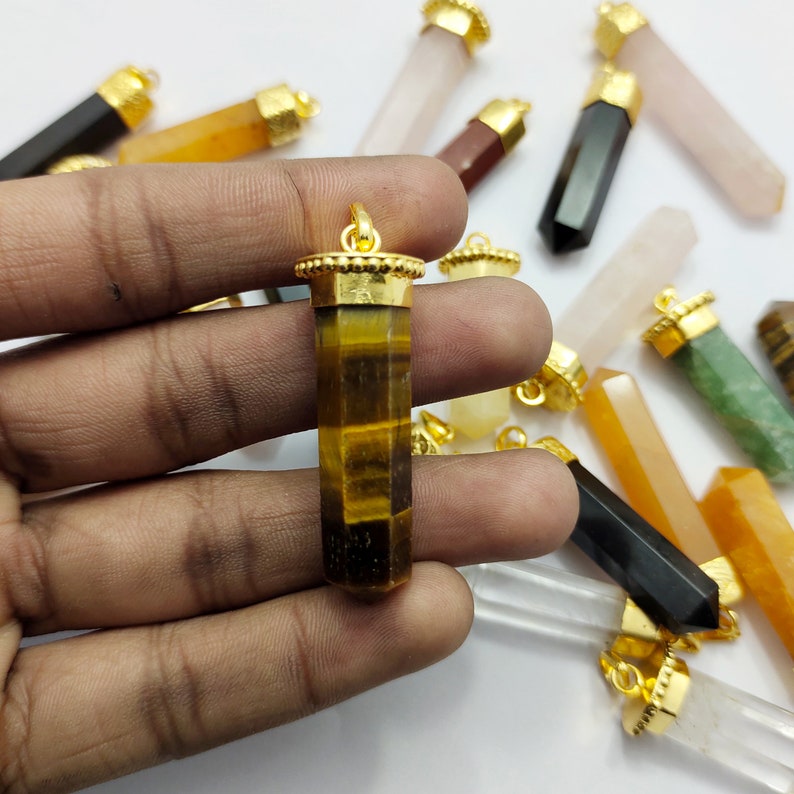 May include: A collection of gemstone pendants with gold caps, including tiger's eye, clear quartz, rose quartz, and green aventurine.
