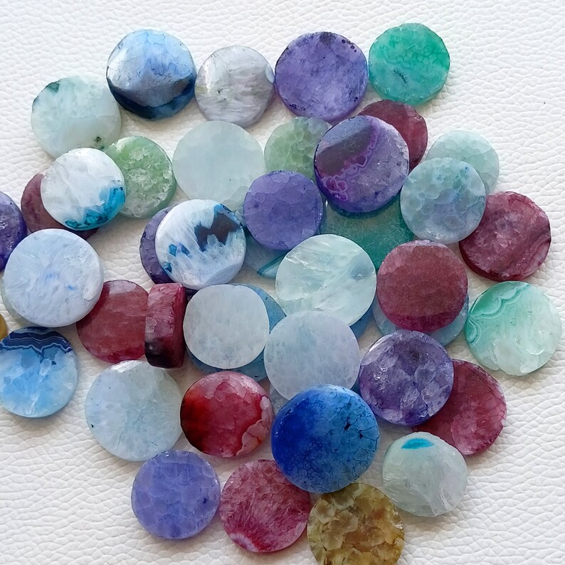 May include: Assortment of round agate slices in various colors, including blue, purple, green, and red. The slices are smooth and polished, with intricate patterns and textures.