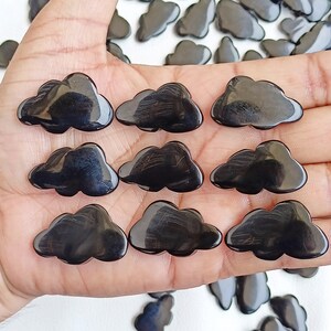 May include: A collection of nine black cloud-shaped polished stones. The stones are smooth and have a glossy finish.