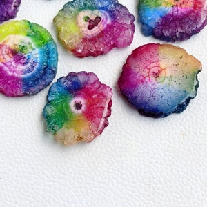 May include: Assortment of rainbow agate slices with a variety of colors and patterns. The slices are smooth and polished, with a natural crystal formation.