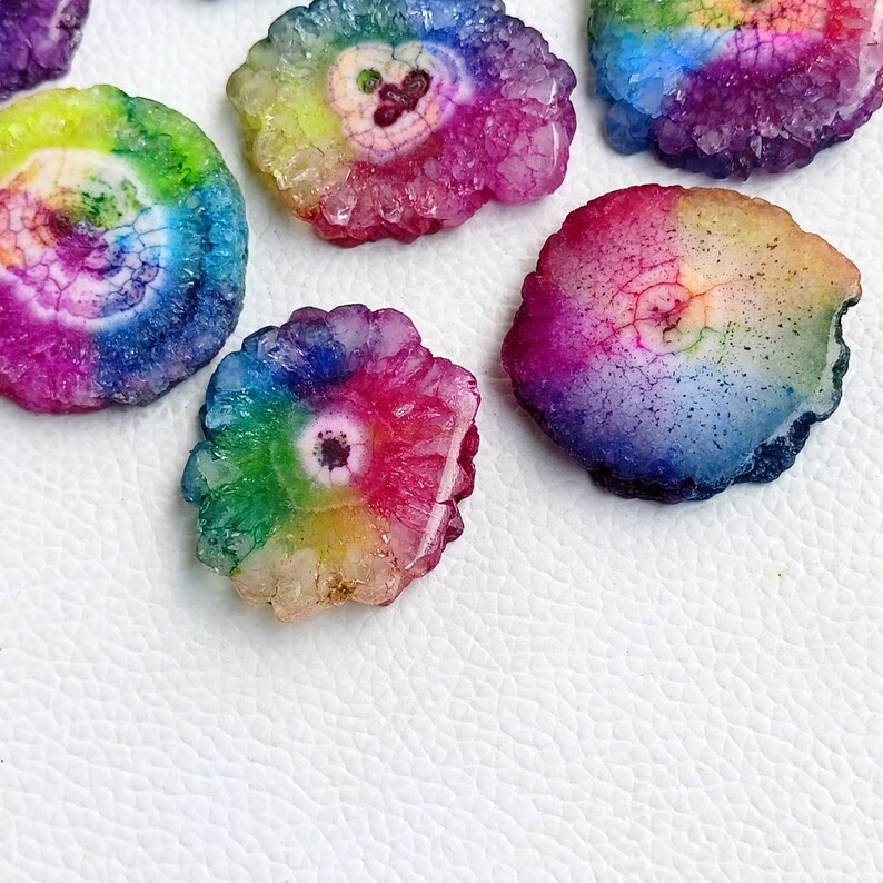 May include: Assortment of rainbow agate slices with a variety of colors and patterns. The slices are smooth and polished, with a natural crystal formation.