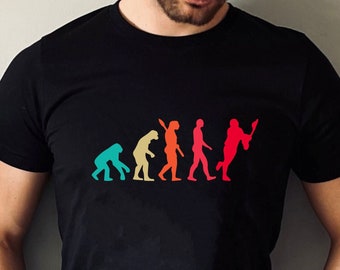 May include: A black t-shirt featuring a graphic of the evolution of man, culminating in a person playing lacrosse. The graphic is in a rainbow colour scheme.