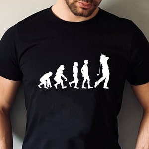 May include: A black t-shirt featuring a white graphic of the evolution of man, culminating in a golfer holding a club.