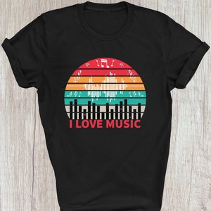 May include: Black t-shirt featuring a vintage-style graphic of a sunset with sound waves and musical notes. The text "I LOVE MUSIC" is printed below the graphic.