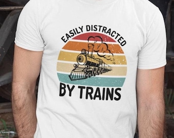 May include: White t-shirt with a vintage-style graphic of a train with the text "Easily Distracted By Trains".