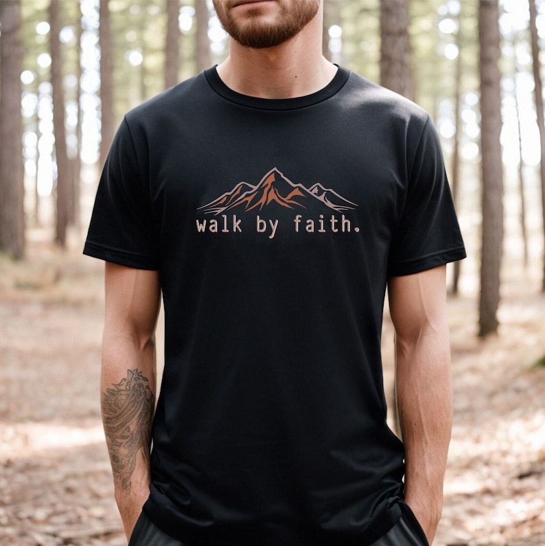 Peut inclure: Un t-shirt noir avec un motif de cha&icirc;ne de montagnes brun et le texte "walk by faith."