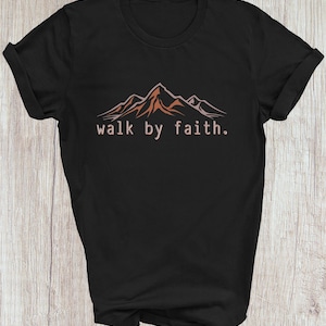Peut inclure: T-shirt noir avec un motif de cha&icirc;ne de montagnes et le texte "walk by faith."