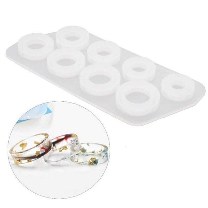 May include: White silicone mold with six round ring shapes. The mold is used to create resin rings. Four finished resin rings with different colors and designs are shown.