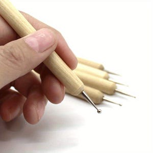 May include: A collection of dotting tools featuring wooden handles and metal tips. The tips are designed with varying sizes of rounded ends, ideal for crafting dots and patterns in diverse projects. The tools are displayed against a white backdrop.