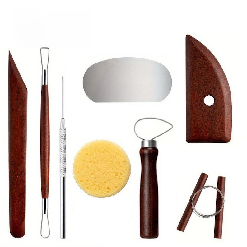 May include: A set of pottery tools, including wooden modeling tools, a needle tool, a sponge, a wire cutter, and a loop tool. The tools are arranged on a white background, showcasing their various shapes and functions for sculpting and shaping clay.
