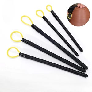May include: A set of five black pottery loop tools with yellow loops. The tools are arranged diagonally on a white surface. The tools are used for trimming and shaping clay in pottery.