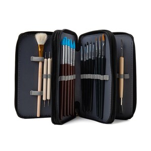 Könnte beinhalten: Ein schwarzes Etui mit Reißverschluss, geöffnet, um verschiedene Kunstwerkzeuge zu zeigen. Das Etui enthält Pinsel mit schwarzen und braunen Griffen und blauen Spitzen. Ebenfalls enthalten sind Holzwerkzeuge und ein großer Pinsel mit goldener Zwinge und weißen Borsten. Das Innere ist grau.