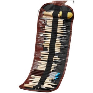 Puede incluir: Un estuche de herramientas de cuero marrón lleno de varias herramientas de escultura. Las herramientas tienen mangos de madera y puntas de metal, incluyendo cuchillas, lazos y cepillos. El estuche está asegurado con una correa negra.