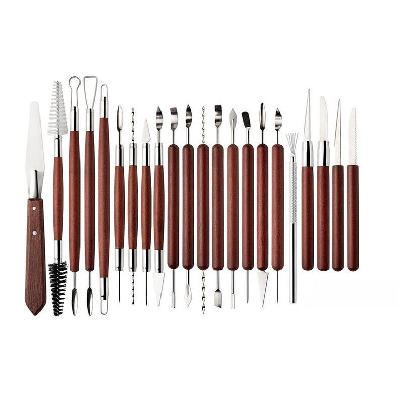 May include: A set of 24 pottery and sculpting tools. The tools have dark brown wooden handles and silver metal tips. The tools include various shapes such as blades, loops, and brushes, ideal for detailed work.