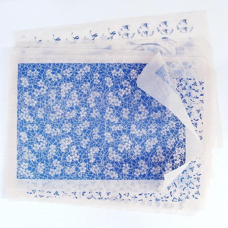 May include: A stack of blue and white patterned tissue paper with a floral design. The tissue paper is folded and the top sheet is partially peeled back.