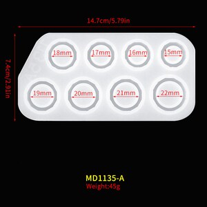 May include: White silicone mold with eight round cavities for making rings. The mold is 7.4 inches long and 14.7 inches wide. The cavities are labeled with measurements in millimeters, ranging from 15mm to 22mm. The mold is labeled "MD1135-A" and "Weight: 45g".