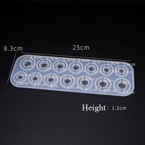 May include: A silicone mold with 12 circular impressions of varying sizes, ranging from 1.4 cm to 3.5 cm in diameter. The mold is 25 cm long and 8.3 cm wide. The mold is 1.2 cm high.