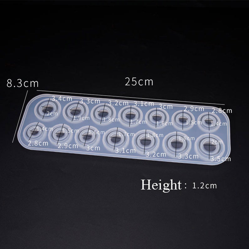 May include: A silicone mold with 12 circular impressions of varying sizes, ranging from 1.4 cm to 3.5 cm in diameter. The mold is 25 cm long and 8.3 cm wide. The mold is 1.2 cm high.