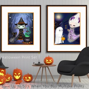 Pu&ograve; includere: Due stampe di Halloween incorniciate. Una raffigura una strega che mescola un calderone con un gatto nero e un ragno. L'altra mostra un fantasma che fa dolcetto o scherzetto con una figura in costume. Il testo "Halloween Print Set" &egrave; visibile.