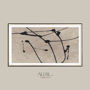 Puede incluir: Impresión de arte abstracto con salpicaduras de tinta negra y líneas sobre un fondo beige. La impresión está enmarcada en un marco negro con un borde dorado.