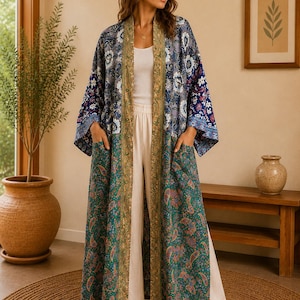 Può includere: Un lungo kimono aperto sul davanti caratterizzato da un design patchwork con una sezione superiore floreale blu e bianca e una sezione inferiore verde con motivo paisley. Il capo presenta un bordo decorativo dorato e due ampie tasche applicate.