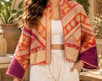 May include: A cropped open-front jacket featuring a quilted texture with a vibrant pattern of orange, red, and cream floral motifs. The garment includes wide sleeves with solid purple cuffs and a mandarin-style collar, worn over a white top and pants.