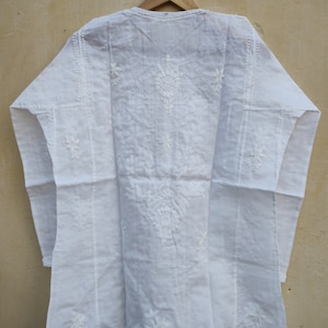 May include: White cotton tunic with white embroidery. The embroidery features a floral design.