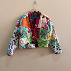 May include: A patchwork jacket with a vibrant mix of colors and patterns. The jacket features a V-neck design and long sleeves. The fabric is a combination of floral, animal, and geometric prints in shades of red, orange, green, and blue.
