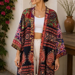 Può includere: Un kimono a maniche lunghe aperto sul davanti con una base blu navy scuro e un vivace motivo paisley e floreale multicolore nei toni del rosso, rosa, verde e giallo. Il capo presenta un orlo dritto, maniche ampie e un bordo a contrasto.