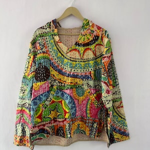 May include: A colorful, patchwork-style quilted top with a V-neck and long sleeves. The fabric features a variety of geometric and floral patterns in shades of blue, green, yellow, orange, pink, and brown.