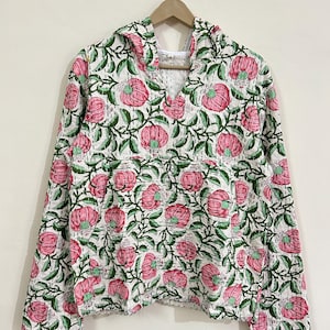 May include: A white hooded sweatshirt with a pink and green floral print. The sweatshirt has long sleeves and a v-neck.