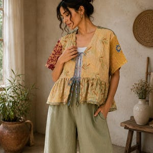 May include: A short-sleeved, open-front jacket featuring a patchwork design with yellow, green, and maroon floral patterns, a ruffled hem, and thin tie closures. The jacket is paired with solid light olive green wide-leg trousers.