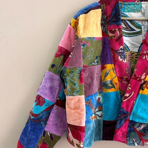 May include: A patchwork jacket with a vibrant mix of colors and patterns. The jacket features a variety of fabrics, including velvet, in shades of pink, blue, purple, yellow, and green. Floral and geometric designs are incorporated into the patchwork.