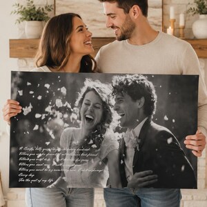 May include: A rectangular canvas print featuring a black and white photograph of a couple laughing outdoors with falling petals. The print includes white cursive text on the left side, displaying a romantic quote about love and life together.